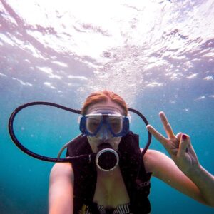 alexx pulling peace sign underwater while scuba diving