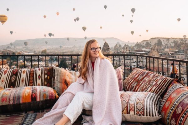 girl sitting in front of cappadocia balloons in turkey