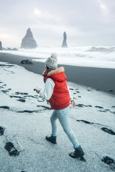 Girl walking in snow on Reynisfjara Black Sand Beach Iceland