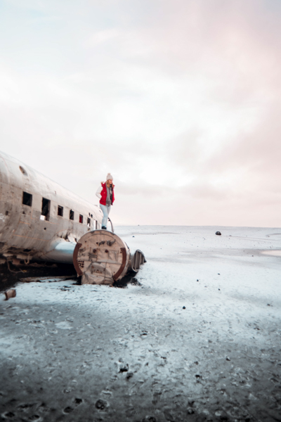 Girl standing on broken plane fuselage in Iceland