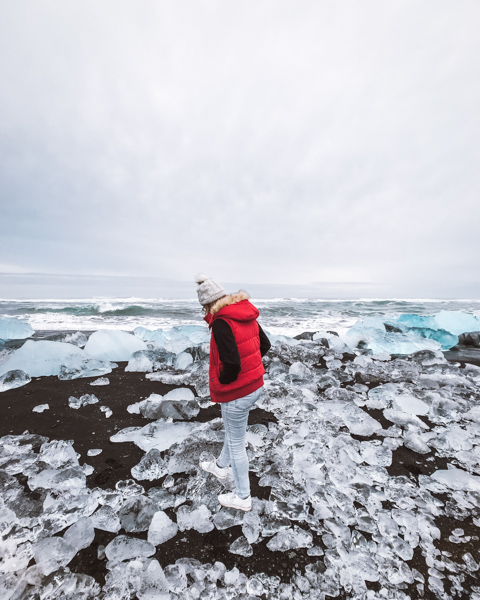 Girl standing on ice blocks on Diamond Beach in Iceland