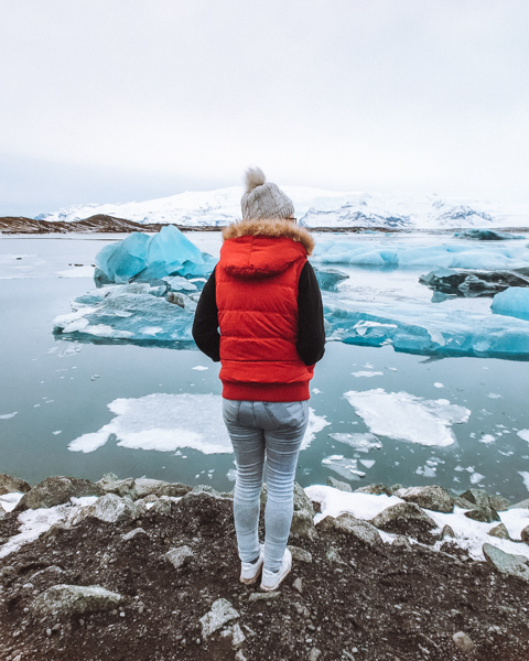 Girl standing in front of icebergs at Jokulsarlon Glacier in Iceland