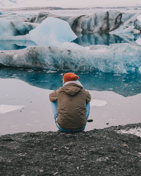 Man sitting in front of Jokulsarlon Glacier in Iceland