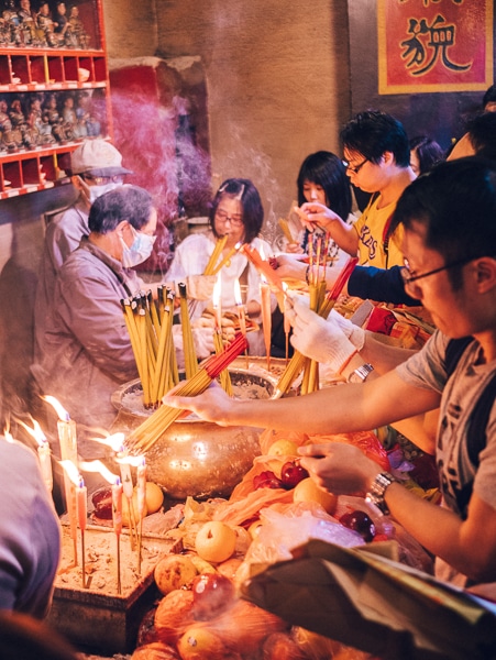 People lighting incense and candles in temple in Hong Kong