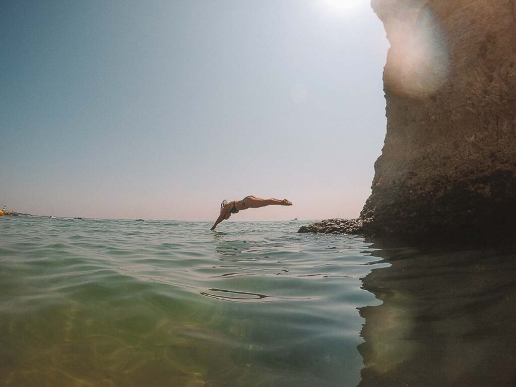 Girl diving into water in Algarve Portugal