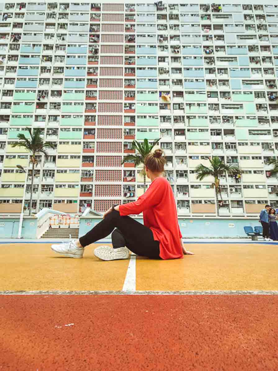 Girl sitting in front of colourful building in Hong Kong