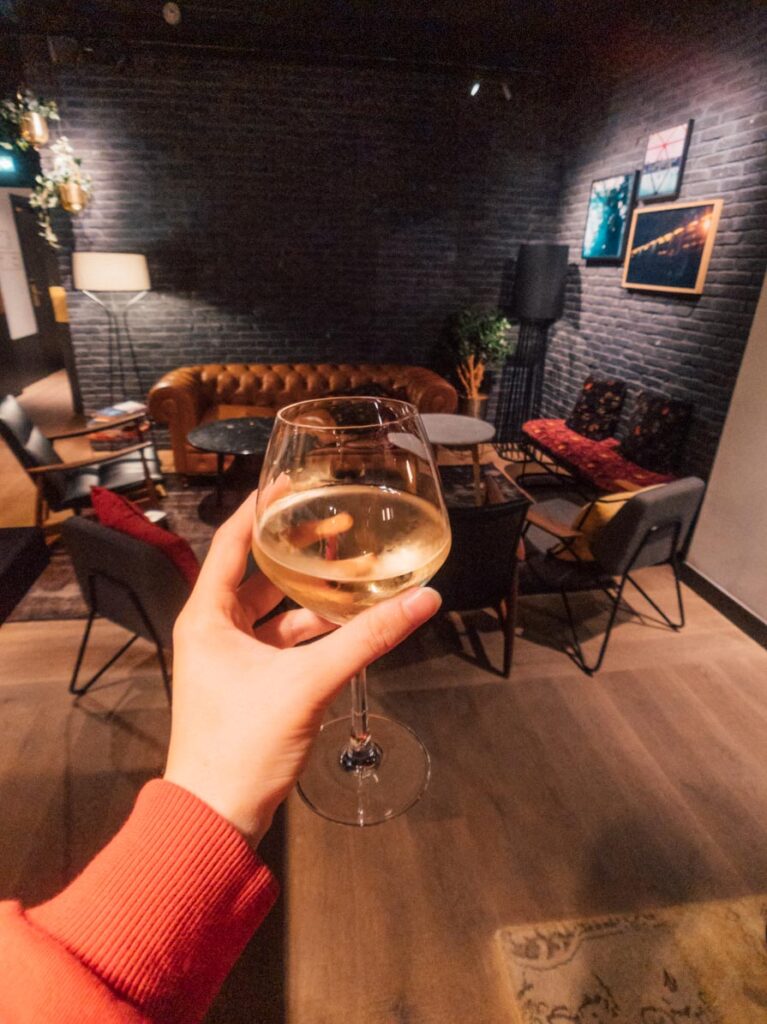 Girl holds wine glass in front of hotel bar