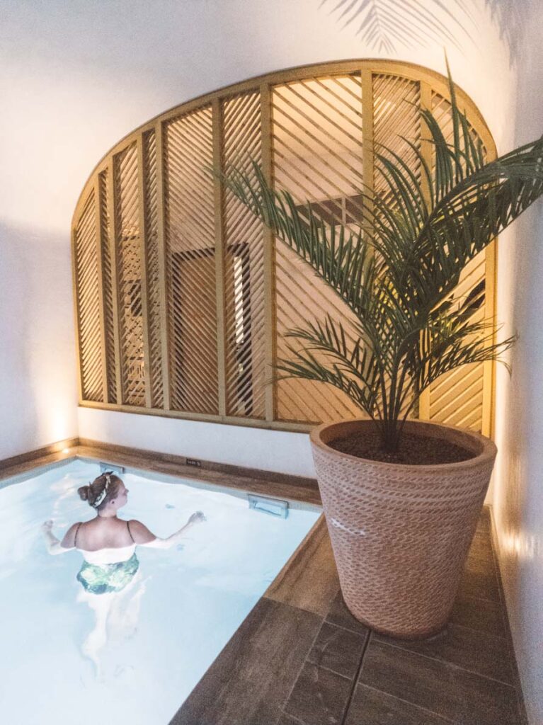 Girl swimming in indoor pool next to palm tree