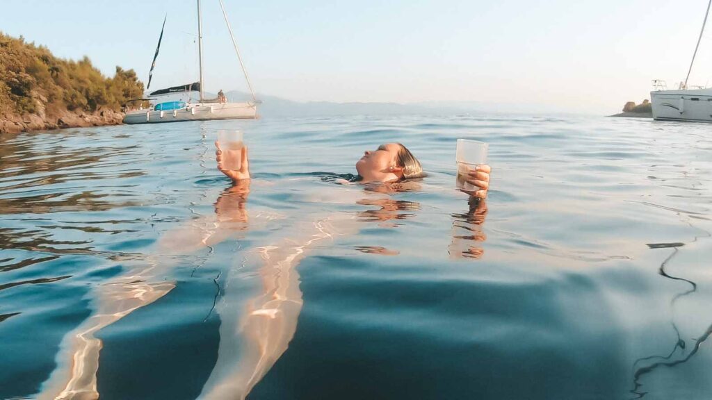 Girl floating with two drinks in her hands