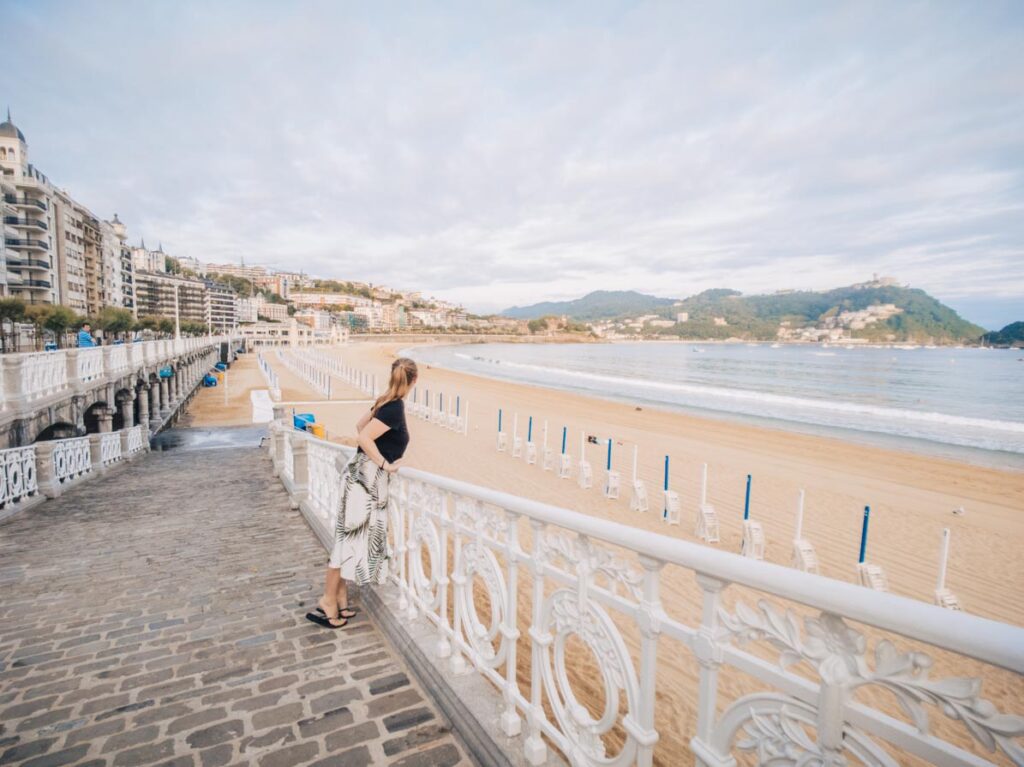 Girl leaning on railing in front of La Concha beach in San Sebastian