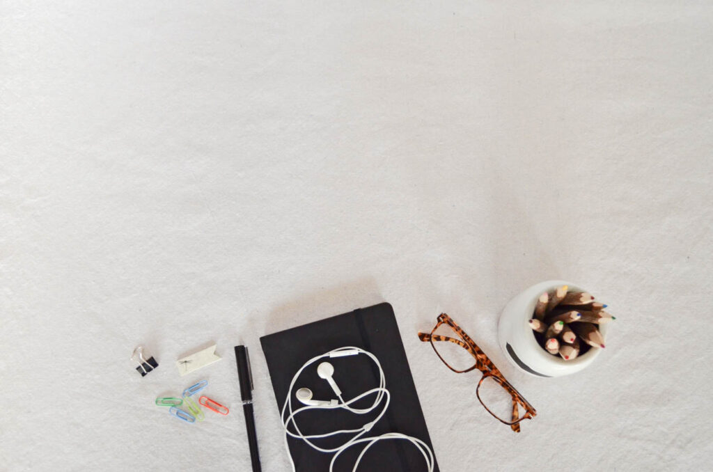 Flatlay of glasses, book, pen and paper clips