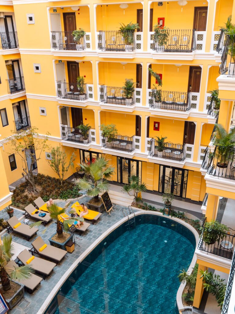 An aerial view of a yellow hotel with a central swimming pool in Hoi An, showcasing the peaceful atmosphere of the accommodation.