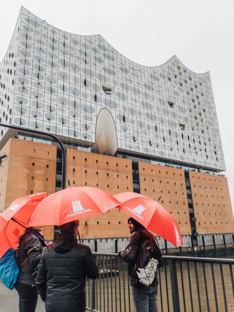 Tourists with umbrellas in front of the Elbphilharmonie opera house in Hamburg