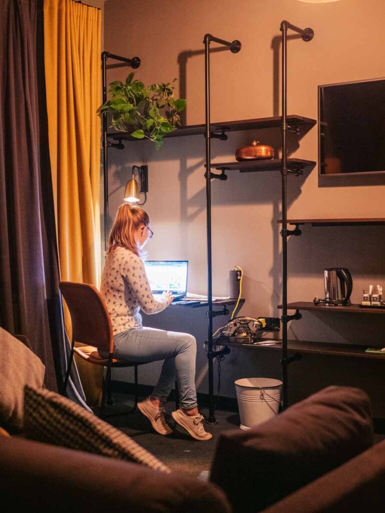 Girl sitting at desk on laptop in 25hours Hamburg hotel