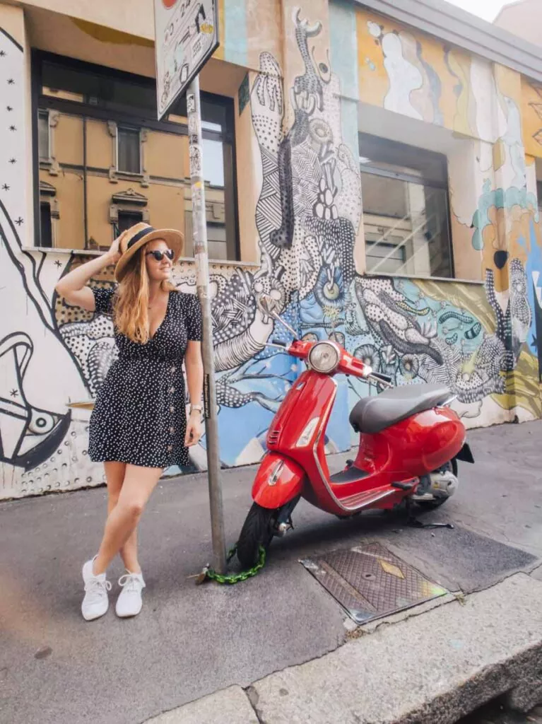 Girl and vespa in front of street art in Milan Isola