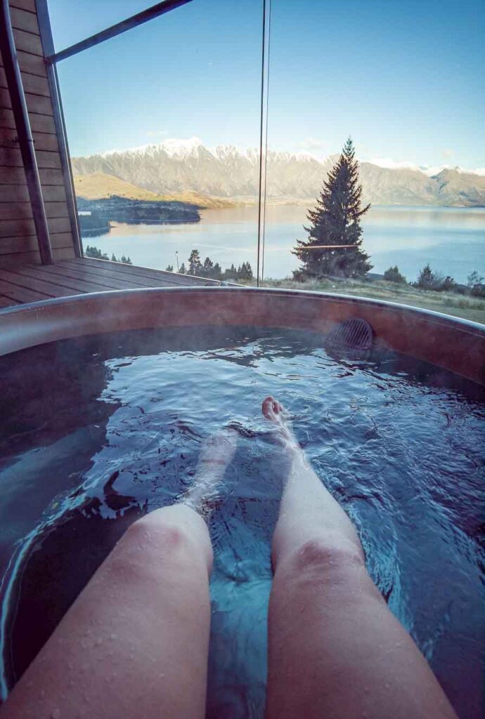 Girl's legs in hot tub in Queenstown with mountains in the background
