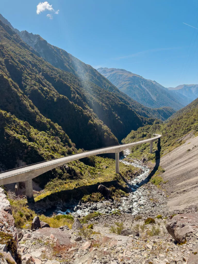 The engineering marvel of the Otira Viaduct stretches across a steep alpine valley in Arthur’s Pass National Park, surrounded by rugged mountain peaks