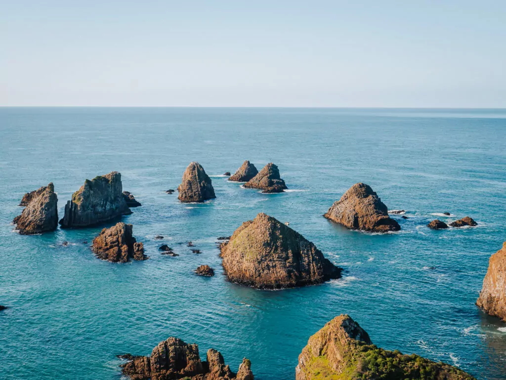 Dramatic rocky sea stacks and islets jutting from the turquoise waters of Nugget Point with steep coastal cliffs in the Catlins