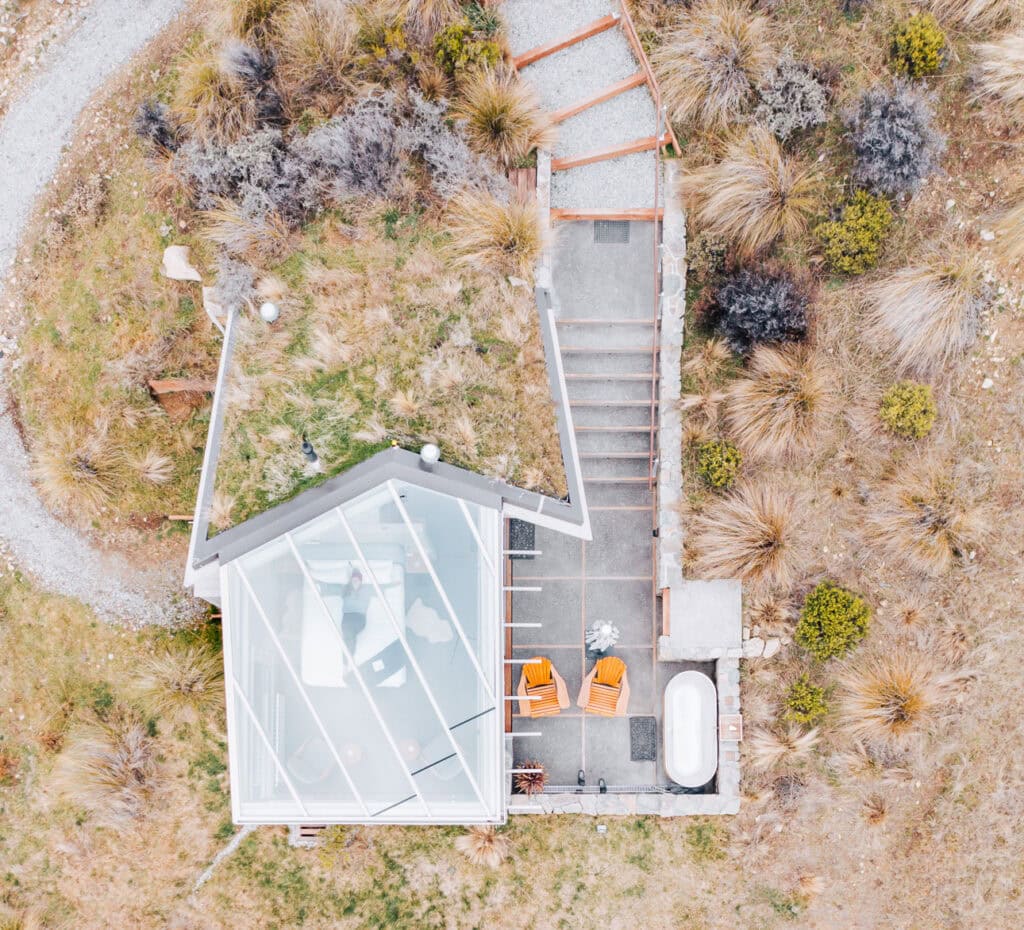 Aerial drone view of SkyScape glass cabin nestled in tussock near Twizel