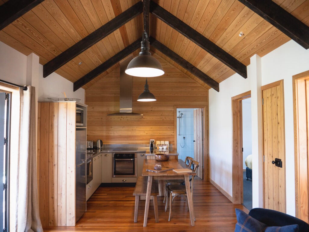 Open plan kitchen and dining area inside an Alpine Lodge at The Cairns with vaulted timber ceiling