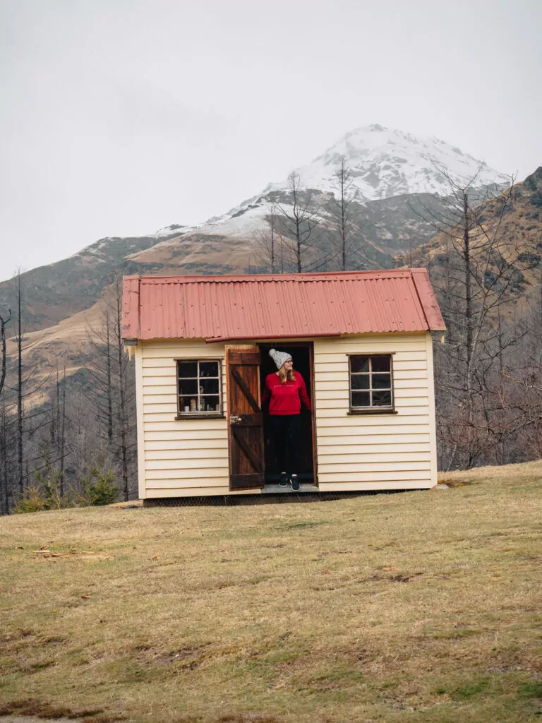 Small rustic wooden shed on a tussock-covered hill in the Queenstown backcountry.