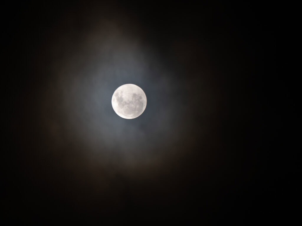 The full moon glowing brightly in the night sky above Lake Tekapo