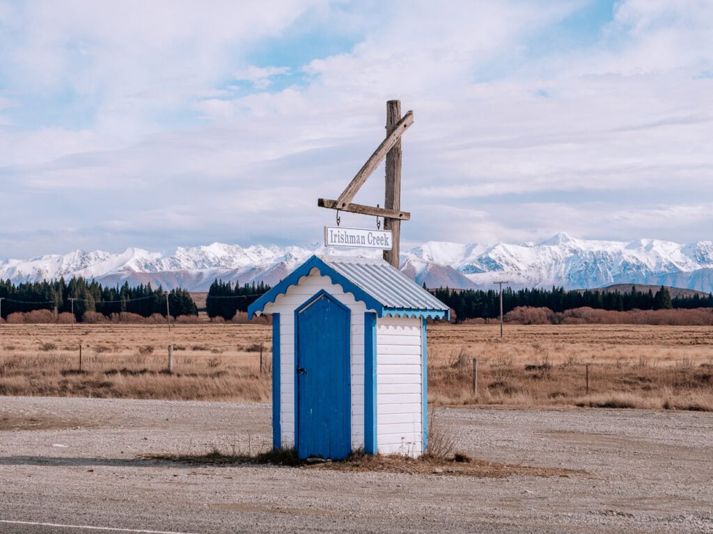 Blue and white historic hut beside Irishman Creek on the drive between Tekapo and Twizel