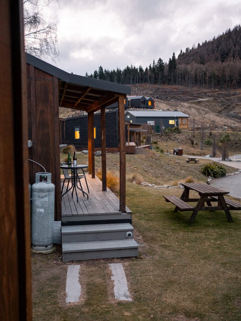 Covered deck of a cabin at Lakes Edge Holiday Park with picnic table and lake views
