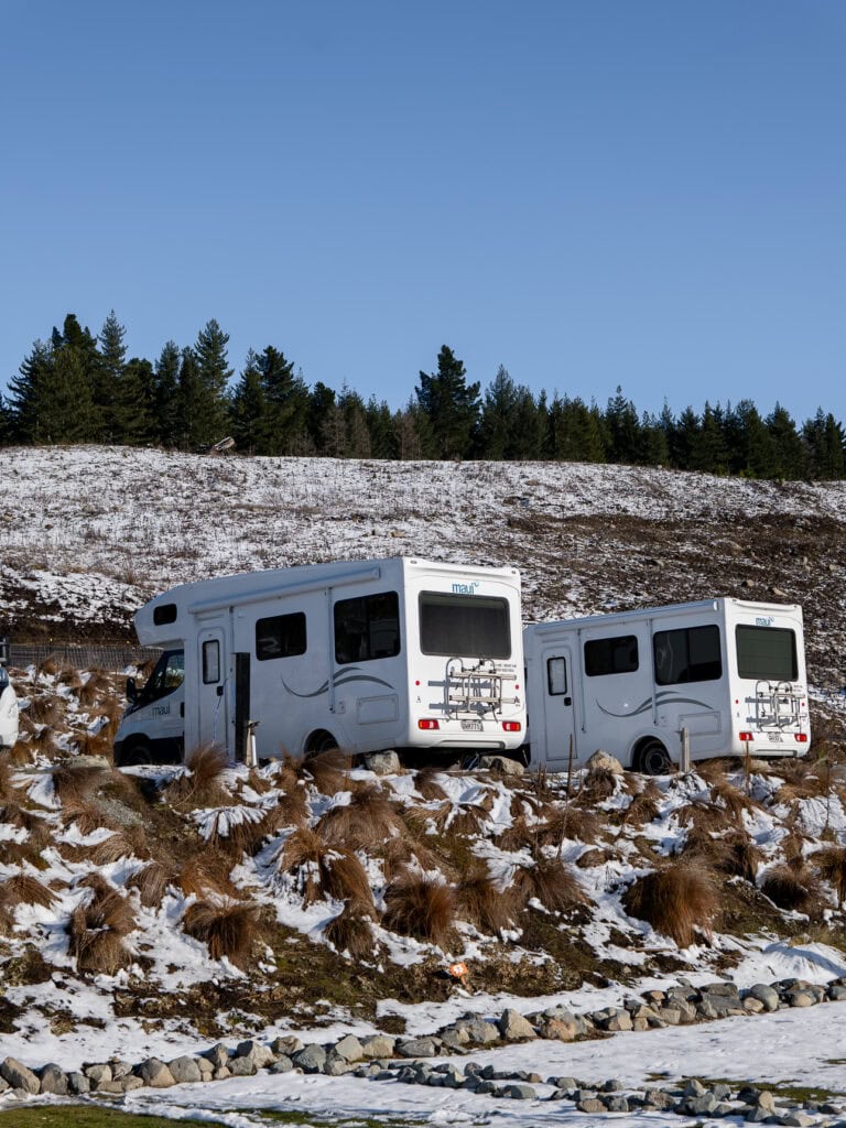 A campervan parked at Lakes Edge Holiday Park in Tekapo with the lake and mountains in the background