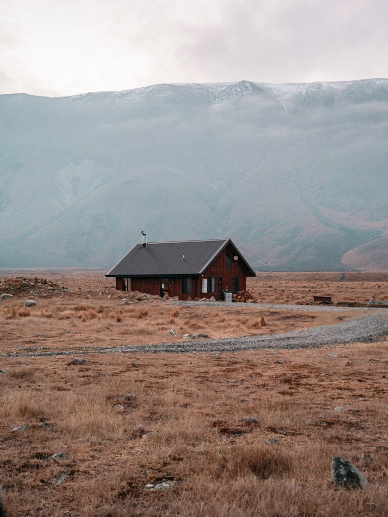 Exterior of the black High Country Cabin sitting alone in the tussock landscape near Twizel