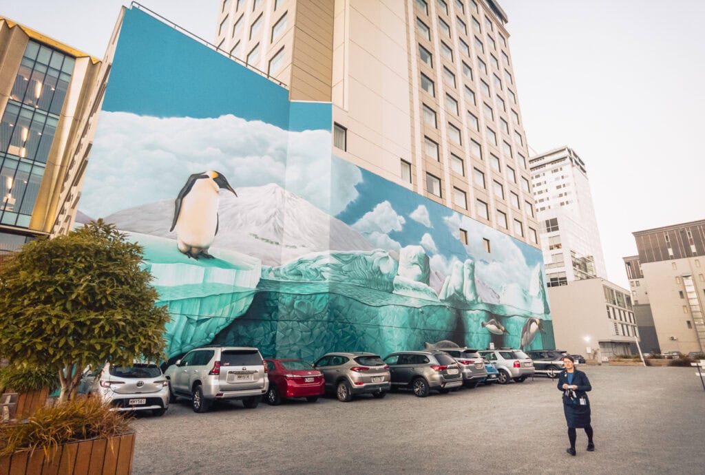 Large blue mural of penguins and ocean life covering the side of a tall building in Christchurch city