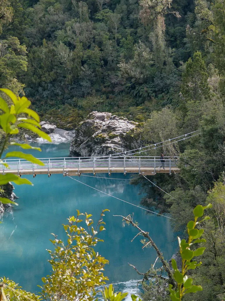 Suspension bridge stretching across the turquoise waters of Hokitika Gorge surrounded by lush native bush