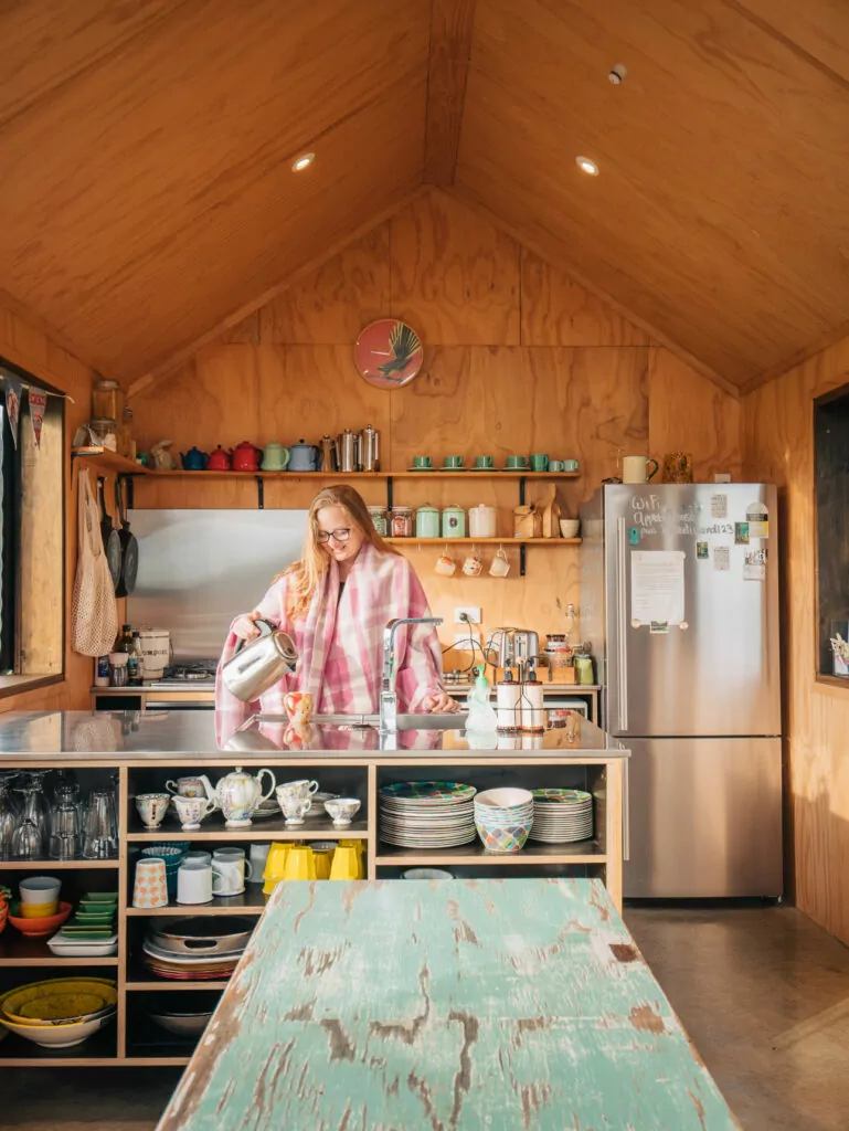 Cozy cabin kitchen with wood-panel walls, open shelves, and breakfast setup inside Rabbit Island Huts