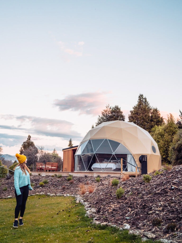 Geodesic dome accommodation at Cross Hill Lodge near Lake Hāwea with a guest looking toward the morning sky