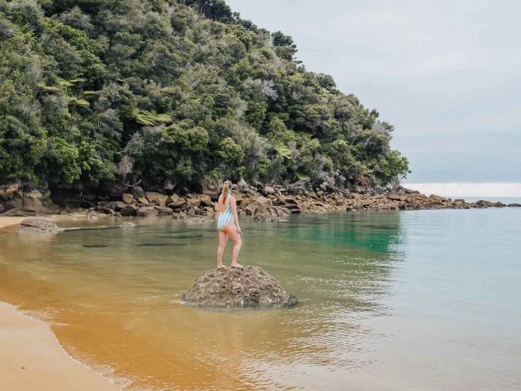 girl standing on rock at abel tasman beach