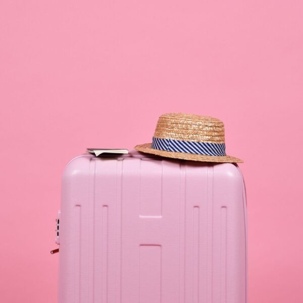 pink suitcase with hat on top