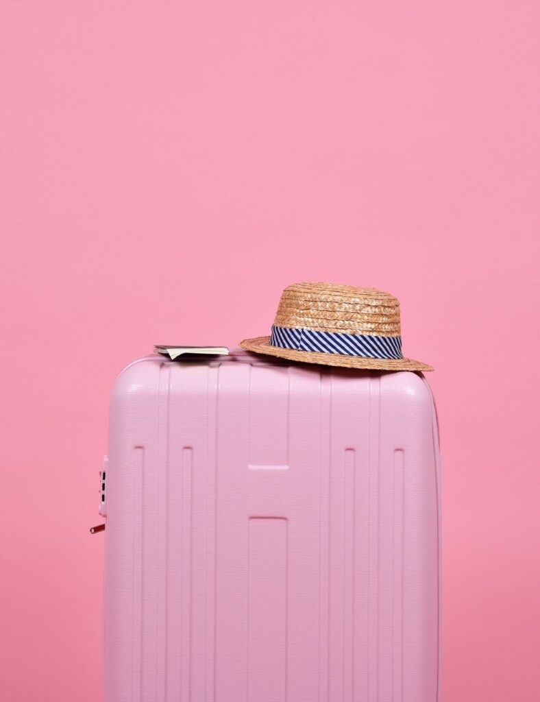pink suitcase with hat on top
