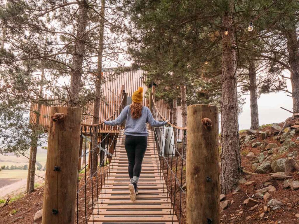 girl walking on bridge towards nest treehouse