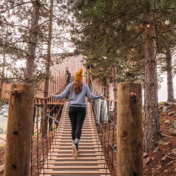 girl walking on bridge towards nest treehouse