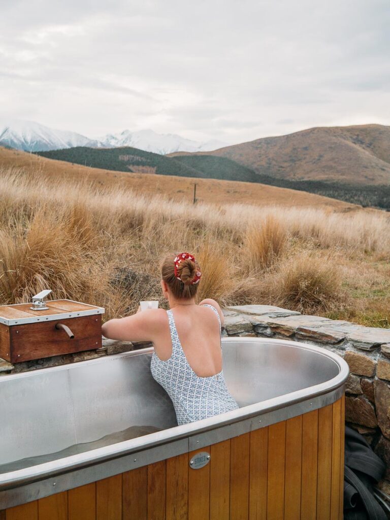 girl in outdoor bath in front of snowy mountains in twizel