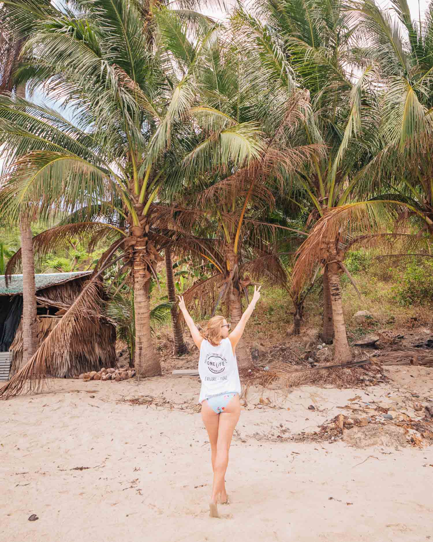 Alexx in a One Life Adventures singlet on a palm-lined beach in the Philippines