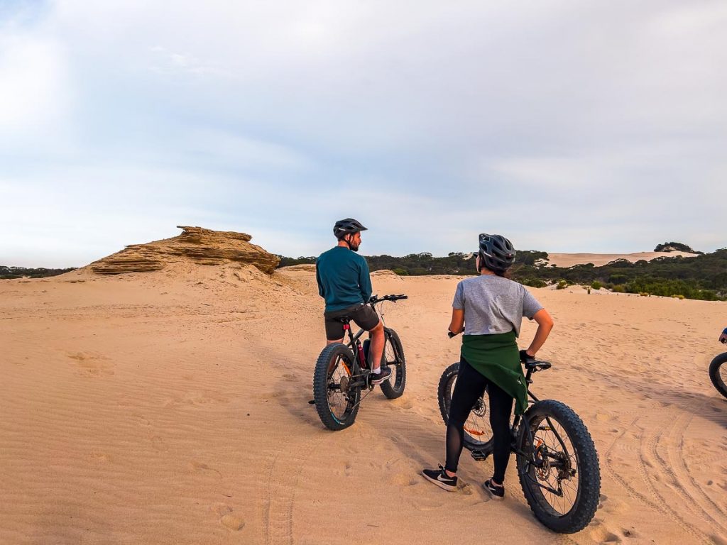 a man and a woman on e-bikes in the sand dunes in kangaroo island