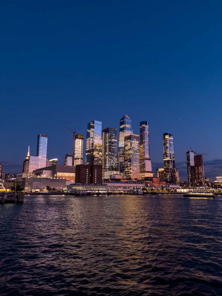 the new york city skyline at night from a harbour cruise