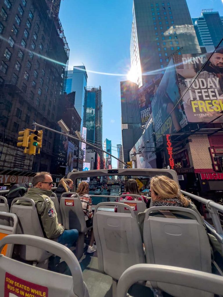 people sitting on an open-top double decker bus in new york city's times square