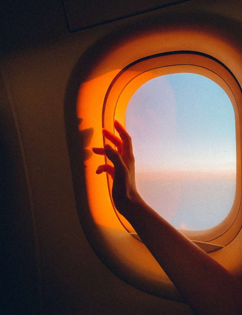 hand in front of sunlight coming through airplane window