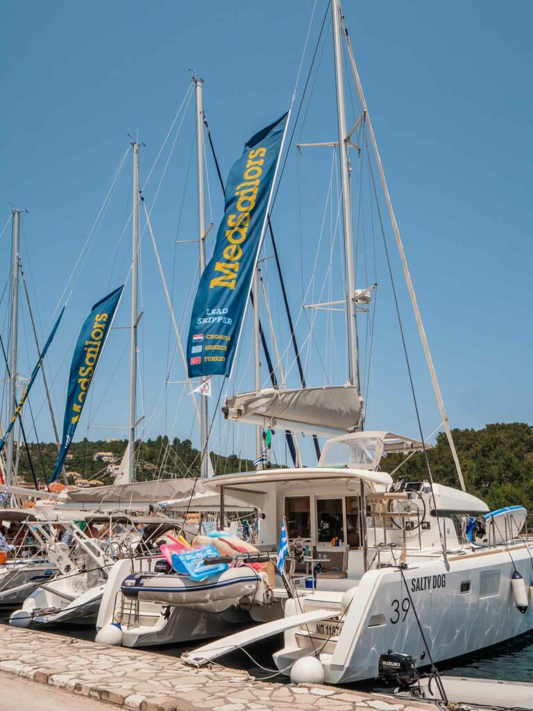 MedSailors yachts docked at a marina in Greece, with the company's flags fluttering in the breeze, signaling the start of an adventurous sailing tour in the Ionian Sea