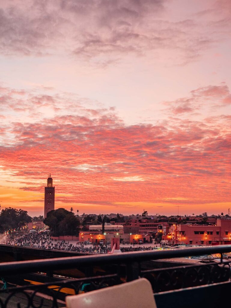 A stunning Marrakech sunset painting the sky in shades of pink and orange, viewed from a rooftop, highlighting the romantic things to do in Marrakech