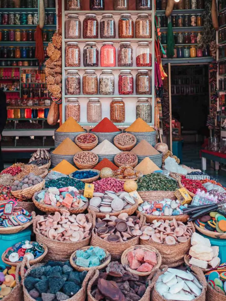 A spice stall in Marrakech displays an abundant array of vibrant spices, dried fruits, and traditional goods, a sensory delight for visitors exploring the local markets