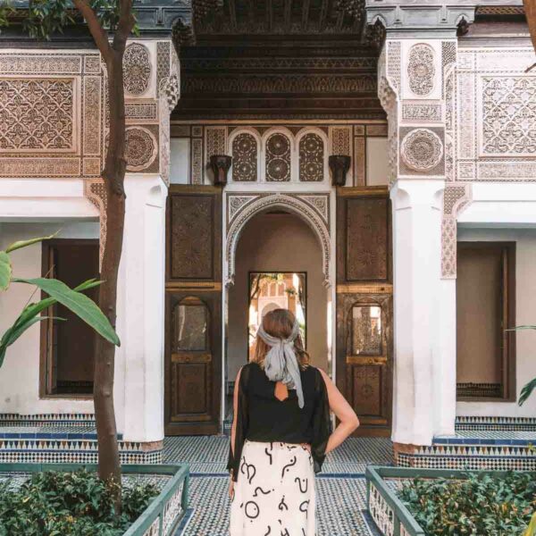 A solo female traveller stands in contemplation in the tranquil courtyard of Bahia Palace, embodying the spirit of adventure in Marrakech