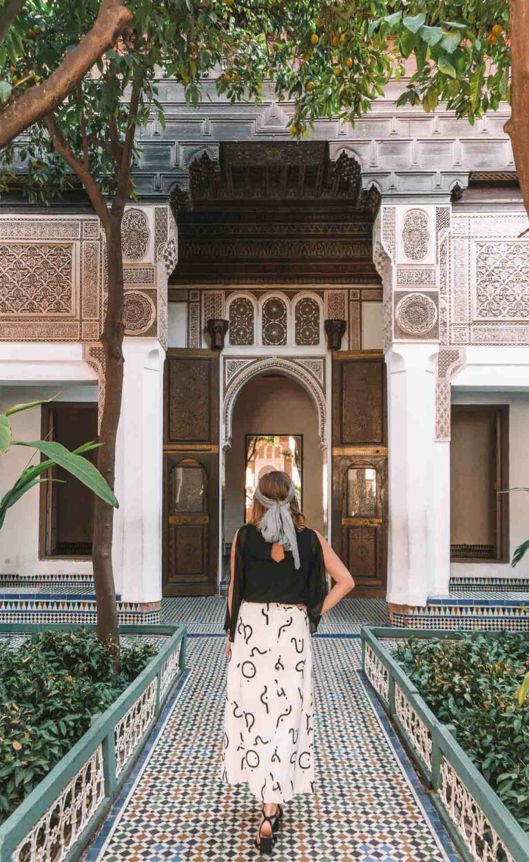 A solo female traveller stands in contemplation in the tranquil courtyard of Bahia Palace, embodying the spirit of adventure in Marrakech